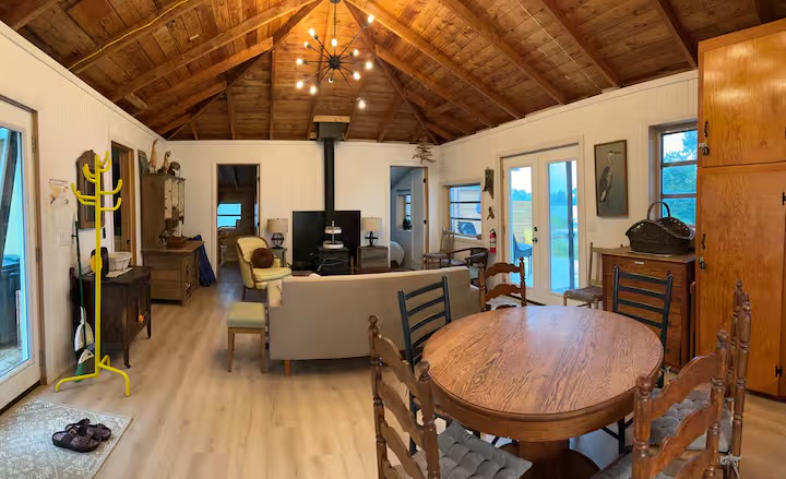Open-concept cottage living and dining room under a vaulted wood ceiling