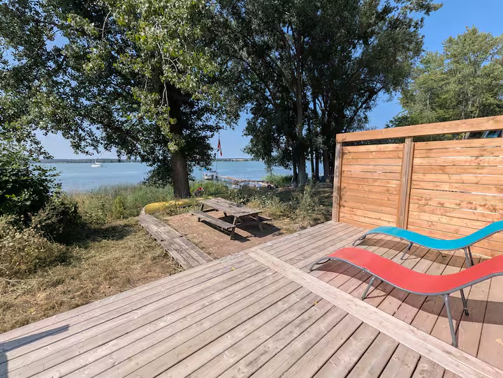 Waterfront fire pit and lounge chairs shaded by mature trees
