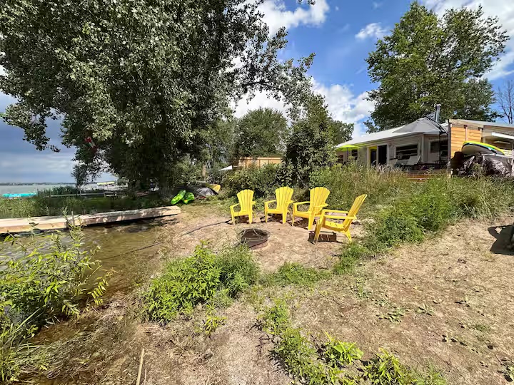 Waterfront fire pit, yellow chairs, cottage, and kayaks