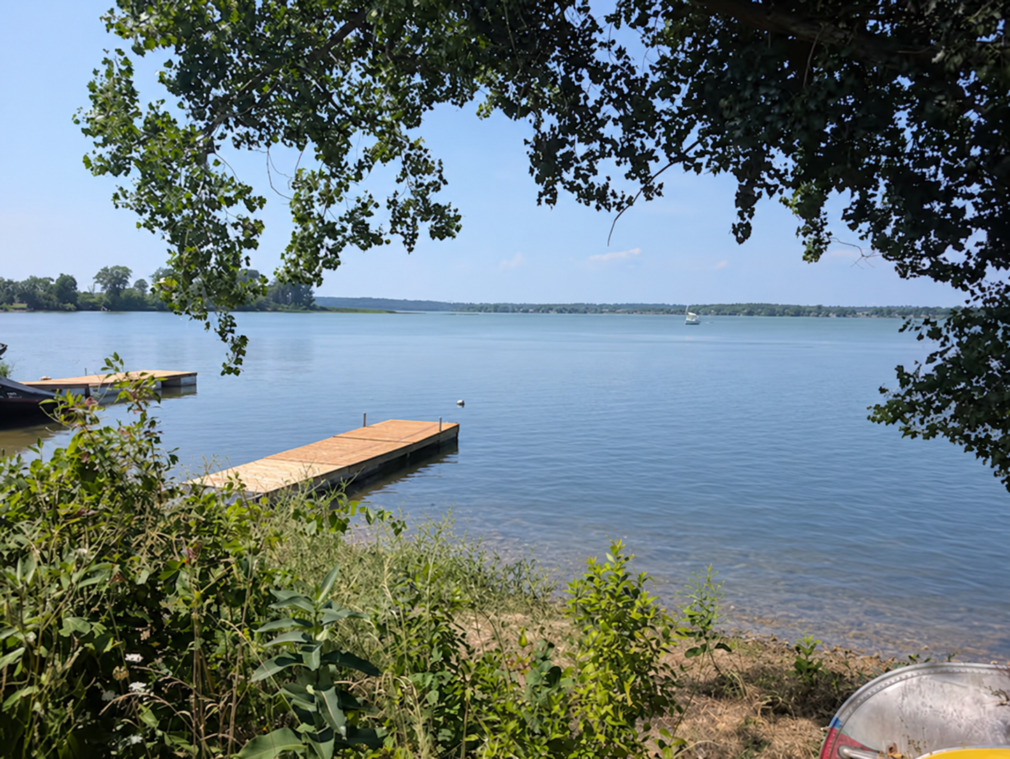 Calm Hay Bay and a wooden dock framed by leafy trees at Walleye Cove